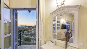 A balcony with a city view, a white vanity with a mirror, and a vase with dried plants. - Aerides 3 Luxury Suites - the heart of the historic center, with Acropolis view (Athens)