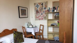 Une chambre à coucher avec un lit, un bureau avec une chaise, une bibliothèque et une porte.