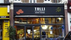 Un bâtiment doté d’une devanture portant l’inscription « TOLLI Patisserie », avec une enseigne représentant une pâtisserie et une feuille.