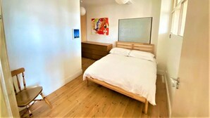 A bedroom with a wooden bed, a chair, a bench, and a painting on the wall. - Splendid 1 Bedroom Flat + Terrace (Kentish Town) (London)
