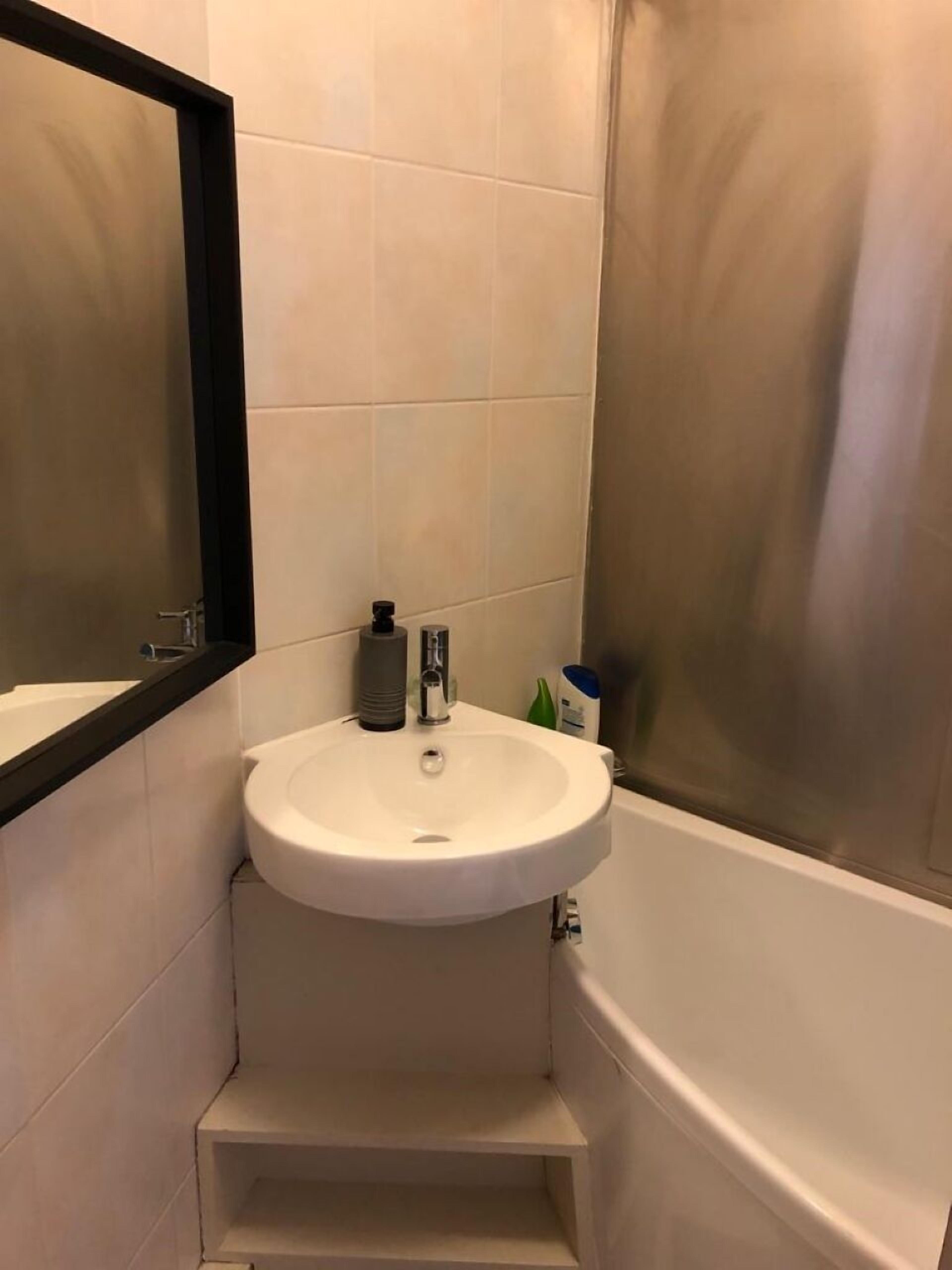 A bathroom with a white sink, a mirror, and a bathtub.