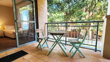 Relax on the balcony with a garden view, featuring a comfortable seating area and a window with a lush garden view.