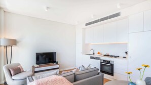 Una sala moderna con un sofá gris, un televisor de pantalla plana y una mesa de comedor con jarrones.