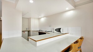 A modern kitchen with a central island, white cabinetry, and a microwave.
