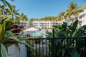 A hotel with a pool, surrounded by palm trees and tropical plants.