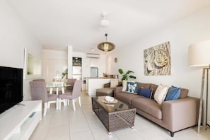 Ein modernes Wohnzimmer mit Sofa, Couchtisch, Fernseher und Essbereich.