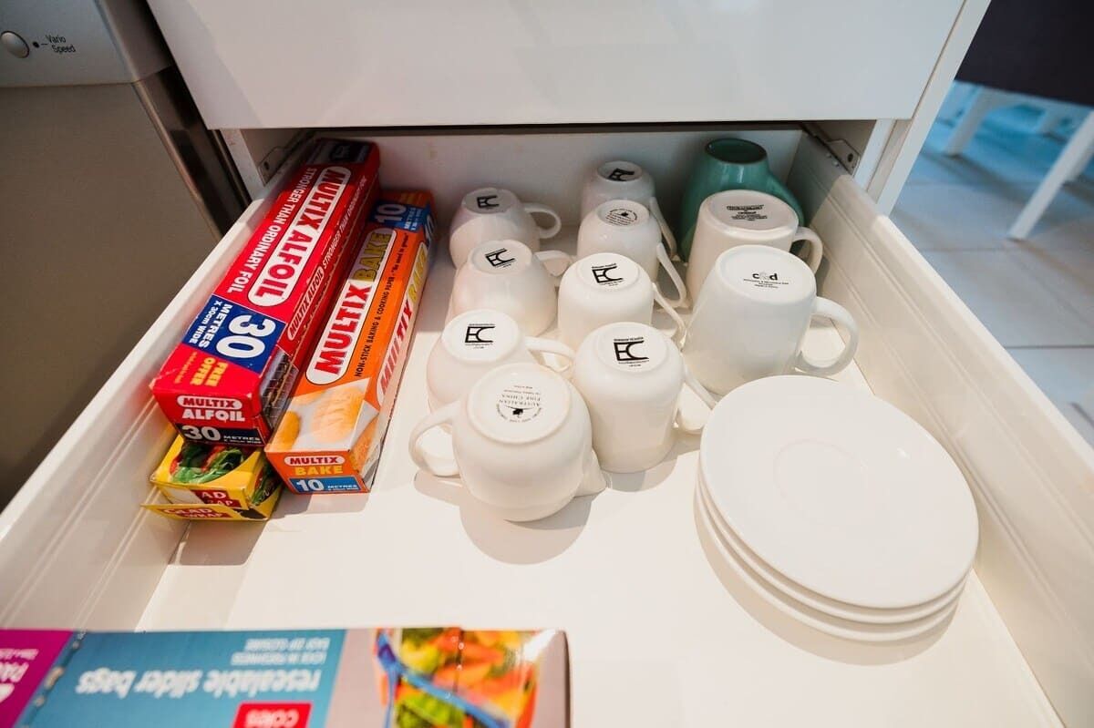 Un cajón con utensilios de cocina, incluyendo teteras, tazas y cajas de harina.