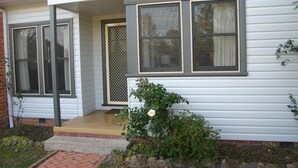 A house with a number '448' sign, a front porch, and a rose bush. - Banksia Cottage - An Old Charm Cottage that has been completely renovated (Albury)