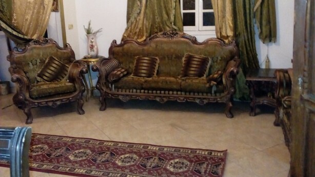 Ein stilvolles Wohnzimmer im klassischen Stil mit einer Vintage-Couch, verzierten Vorhängen und einer Kristallleuchter.