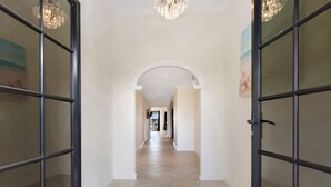A hallway with a tiled floor, a chandelier, and glass doors on either side. - Canal Elegance in Yunderup (South Yunderup)
