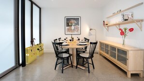 A dining area with a round table, black chairs, and a yellow storage unit with a cartoon character design.