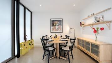 Un coin repas avec une table ronde, des chaises noires et un meuble de rangement jaune orné d’un motif de personnage de dessin animé.