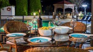 A dining table set outdoors with a bottle of wine, bowls of food, and wine glasses. - VILLA DEMETRA (4 ensuite bedrooms, BBQ, Wi-Fi, Prv. Swim. Pool, stunning view) (Argaka)