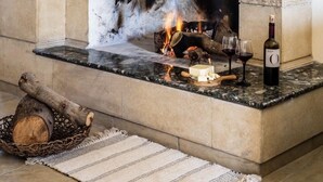 A stone fireplace with a fire burning, a bottle of wine, and a candle on the mantel. - VILLA DEMETRA (4 ensuite bedrooms, BBQ, Wi-Fi, Prv. Swim. Pool, stunning view) (Argaka)