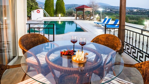 A glass-top table with wicker chairs, a pool, and a gazebo in the background. - VILLA DEMETRA (4 ensuite bedrooms, BBQ, Wi-Fi, Prv. Swim. Pool, stunning view) (Argaka)