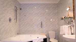 Une salle de bain équipée d’une baignoire, de toilettes et d’un lavabo, le tout recouvert de carreaux de marbre.