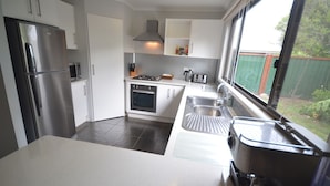 Una cocina moderna con electrodomésticos de acero inoxidable, armarios blancos y un ventanal con vistas al jardín.