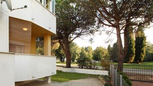 Un bâtiment à deux étages doté d’un balcon, d’une allée gravillonnée et d’un jardin clos avec des arbres.