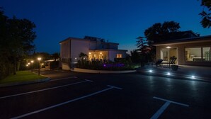Ein modernes Hotel mit gut beleuchtetem Eingang, Parkplatz und angelegten Gärten.