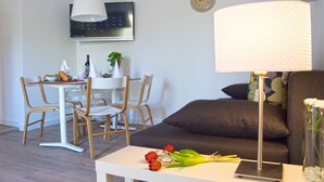Ein modernes Wohnzimmer mit Essbereich, einer Couch, einer Lampe und einer Wanduhr.