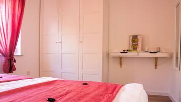 Ein Schlafzimmer mit Bett, Kleiderschrank, Schminktisch mit Spiegel und einer Ablage mit Dekoration.