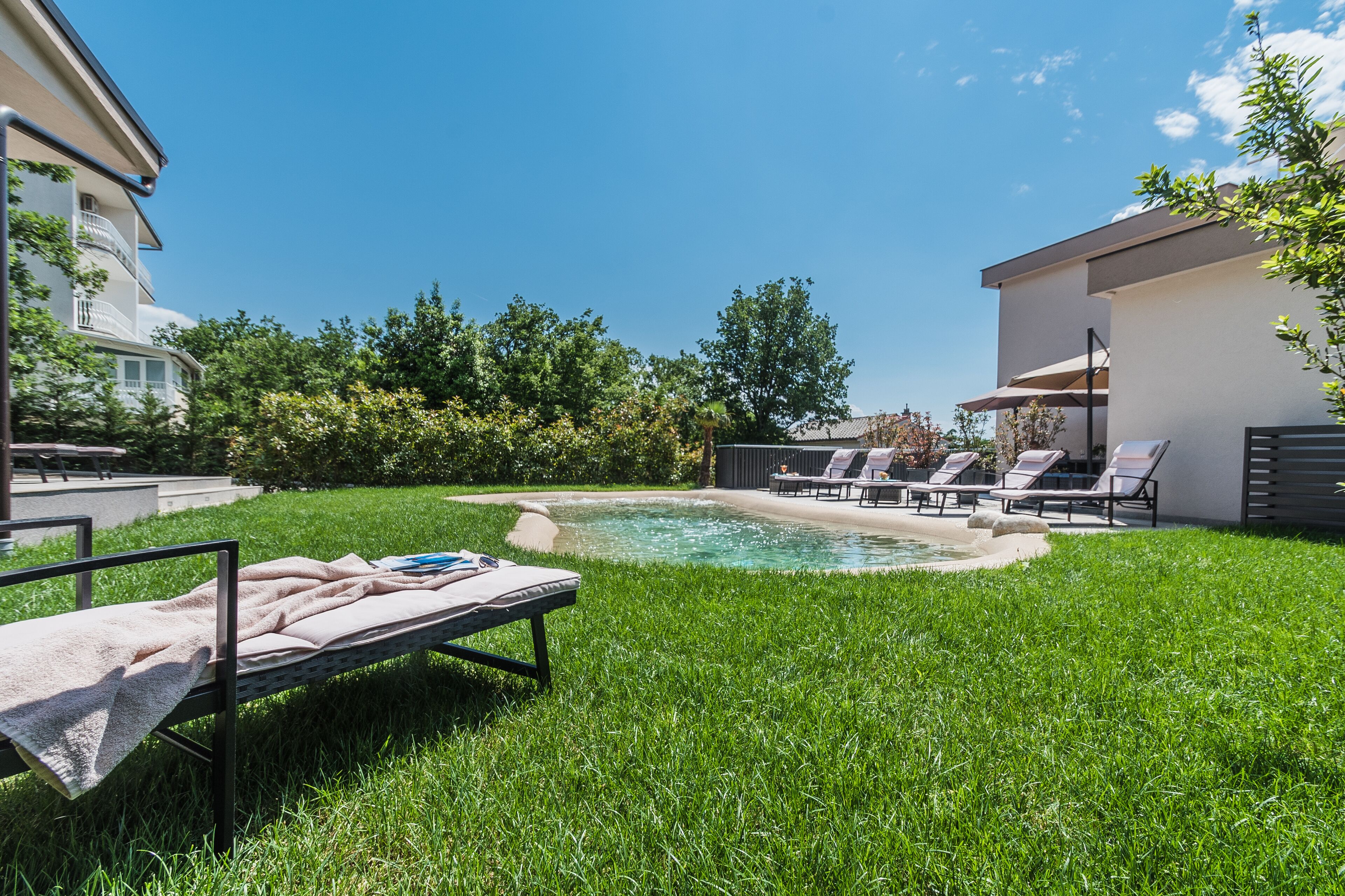 A backyard with a swimming pool, a lounge chair, and a small bed.