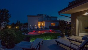 Ein modernes Haus mit Swimmingpool, Sitzgelegenheiten im Freien und einer gut beleuchteten Terrasse.