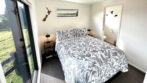 Une chambre à coucher avec un lit, une table de chevet, une fenêtre et une porte.