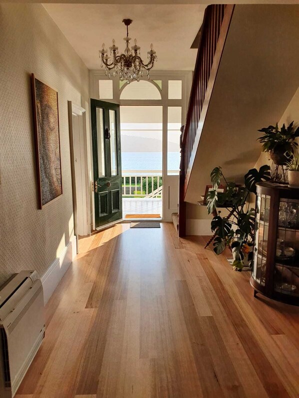 A spacious hallway with wooden flooring, a chandelier, and a view of the outdoors. - Derwent River Villa - the ultimate beach hotel, Hobart (Lindisfarne, Hobart)