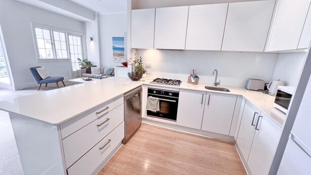 A modern kitchen with white cabinetry, a built-in oven, and a large island with a sink.