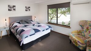 A bedroom with a bed, a desk, a chair, and a window with a view of trees. - SHELLEBRATIONS - Endless Summer (West Busselton)