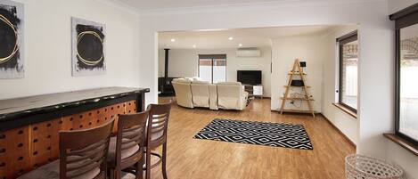 A modern living room with a wooden floor, a black and white rug, a sofa, and a TV.