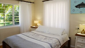 Une chambre à coucher avec un lit, une table de chevet, une lampe, une fenêtre avec des rideaux et un tableau au mur.