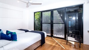 Une chambre d’hôtel avec un lit, un ventilateur de plafond, une porte-fenêtre coulissante et un banc.