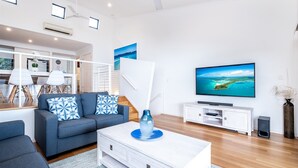 Un salon moderne avec un canapé, une table basse, un téléviseur et un meuble blanc.