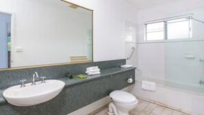 A bathroom with a sink, mirror, toilet, and glass-enclosed shower.