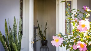 A doorway with a potted plant and a vase of flowers. - Camellia Cottage - Beautiful 3 bedroom cottage with gorgeous gardens - stroll to local cafes! (Cessnock)