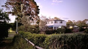 A two-story house with a well-maintained garden and a wooden fence. - Self contained Top Unit - Surfs Up - Hear the sea at night. (Broulee)