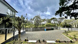 A covered outdoor seating area with tables and chairs, surrounded by a wooden fence and trees. - Self contained Top Unit - Surfs Up - Hear the sea at night. (Broulee)