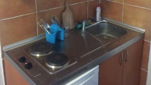A kitchen with wooden cabinets, a stainless steel sink, and a built-in dishwasher. - Cosy apartments surrounded with green space (Petrovac)