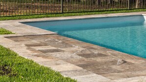 A rectangular swimming pool with a tiled deck and a metal fence in the background. - The Cottage @ Hunter Gleann - Much more than the average cottage! (Pokolbin)