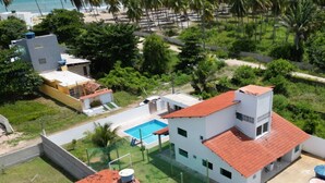 Un quartier résidentiel comprenant plusieurs immeubles, une piscine et, au loin, une plage.