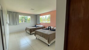 Une chambre d’hôtel avec deux lits, une grande fenêtre et une vue sur la verdure environnante.