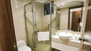 Un baño moderno con ducha de vidrio, inodoro blanco, lavamanos y espejo.