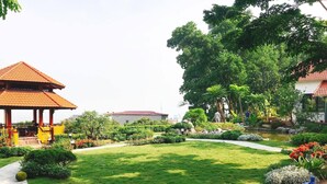 Un jardín bien cuidado con un pabellón, un estanque y una gran variedad de plantas y árboles.