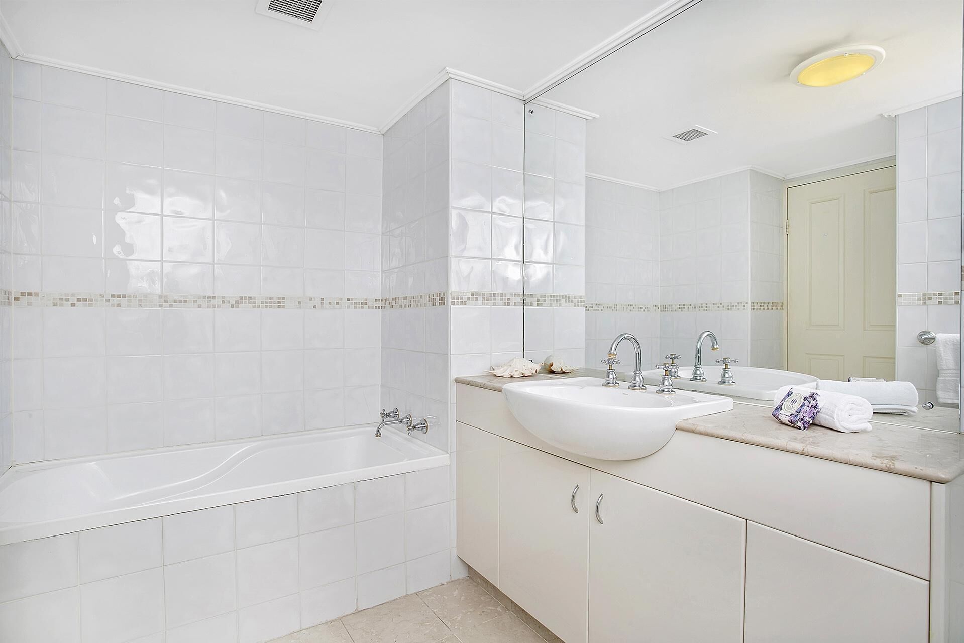 A modern bathroom with a bathtub, two sinks, and a large mirror.