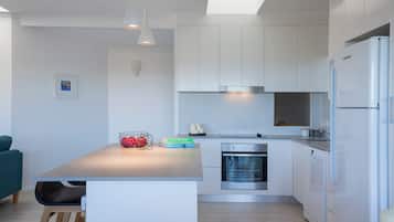 A modern kitchen with white cabinets, a central island, and a built-in oven.