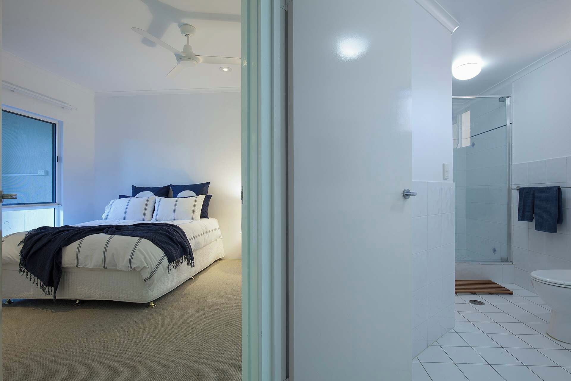 A bedroom with a bed, a ceiling fan, and a window.