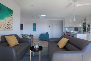 A modern living room with two sofas, a coffee table, and a dining area with a kitchen in the background.