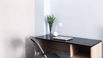 A corner desk with a laptop, a small plant, and a desk lamp.